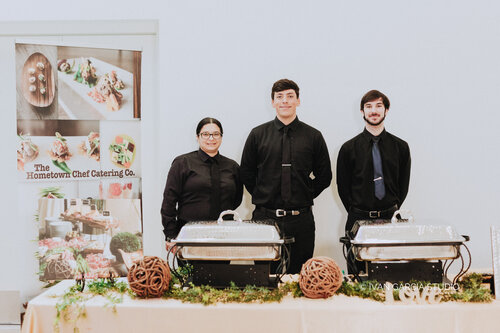 Three people dressed in black is getting ready to cater. 500 by 333 pixels.